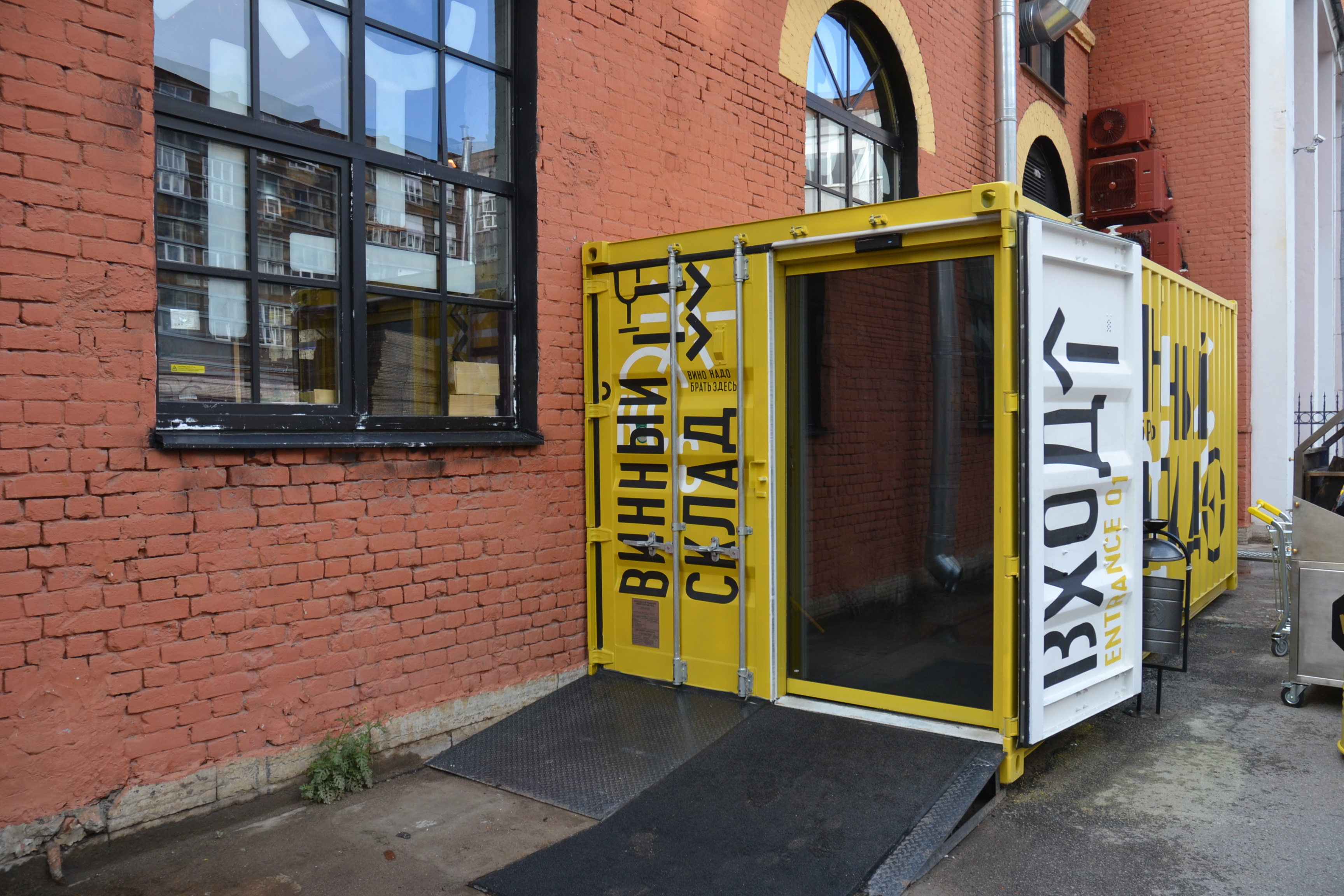 Вход на винный склад оформлен в виде ярко-желтого контейнера, врезанного в здание.